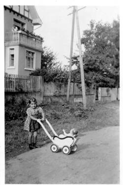 Straßenseite Haus "Bendersch" 1943. Im Vordergrund Renate Dennebaum (H13) mit Puppenwagen, im Hintergrund Haus H42 und Jakob Bender jun. auf dem Balkon.